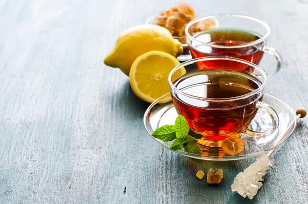 Cup of tea with mint and chrystal sugar on dark rustic copy space background, hot drinks, teatime