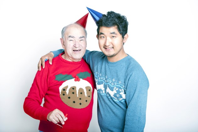 Portrait of a Senior adult man and a young man wearing Christmas jumpers and party hats