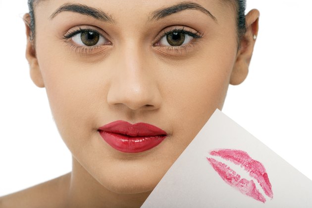 Woman holding a peice of paper with lipstick imprint
