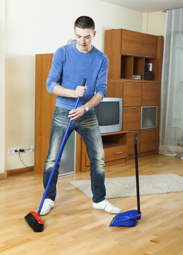 man sweeping the floor at home