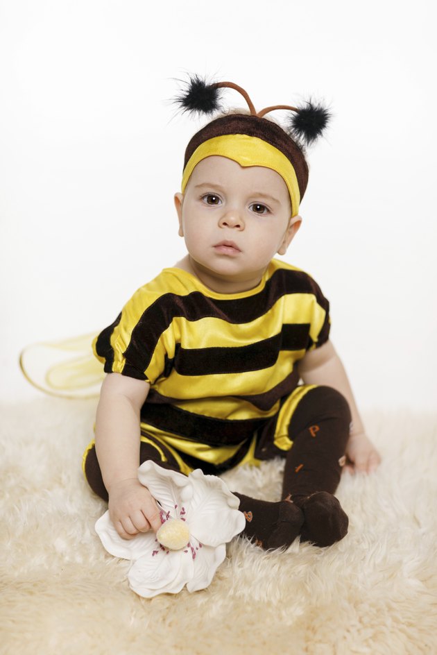 Baby wearing bee costume sitting on the floor