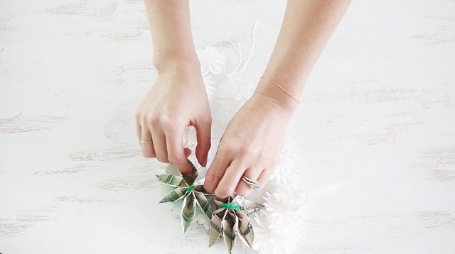 Tying money flowers to lei with pipe cleaners