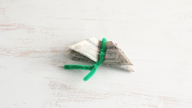 Three bills stacked together and tied with pipe cleaner
