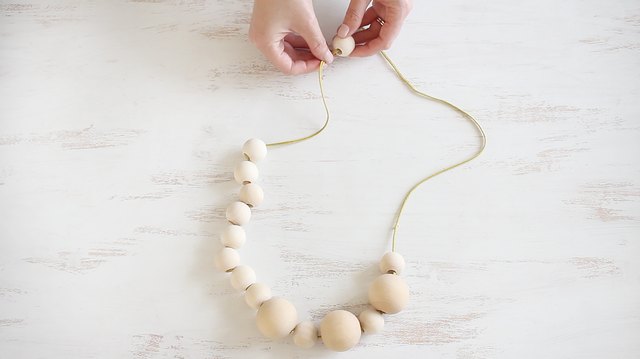String wood beads onto ribbon