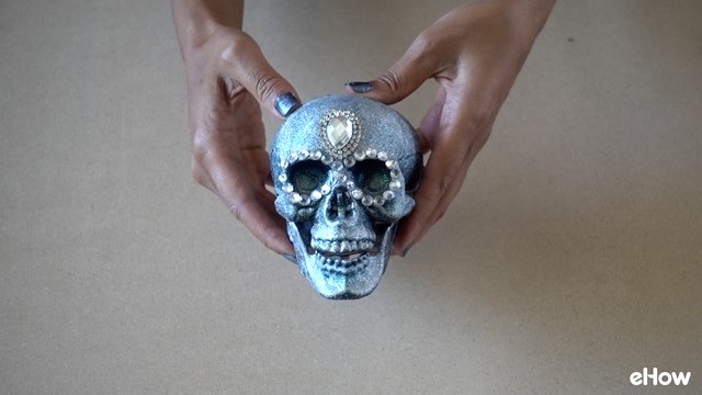 Applying gemstone strip around eyes of plastic skull for DIY Gemstone Studded Halloween Skull
