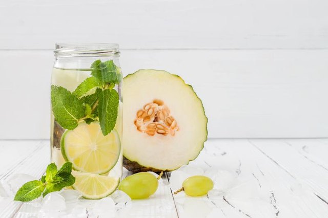 Refreshing homemade lime and mint cocktail over old vintage wooden table. Detox fruit infused flavored water. Clean eating. Copy space background