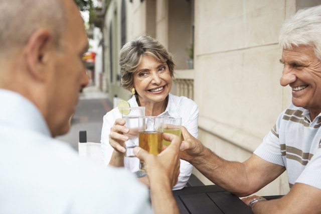 Senior woman and two senior men raising glasses, outdoors, close-up