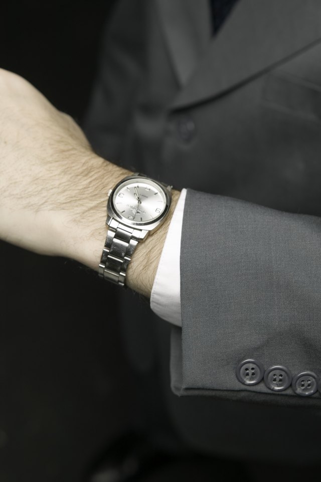 Man checking time, posing in studio, elevated view, close-up, mid section