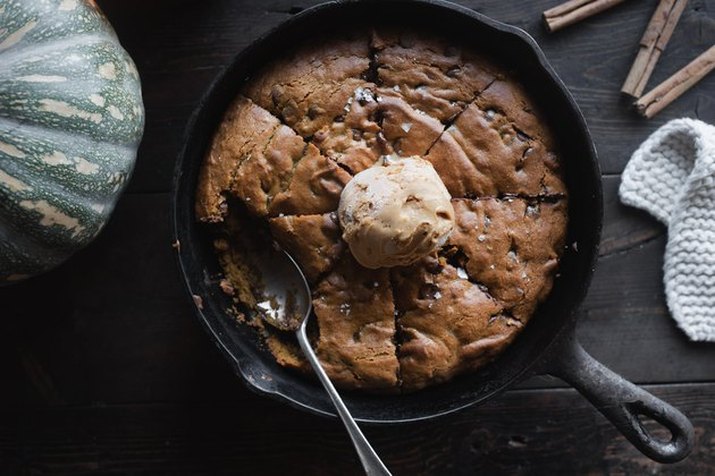 Overhead view of a giant chocolate chip cookie, served in a cast iron skillet, with a scoop of ice cream