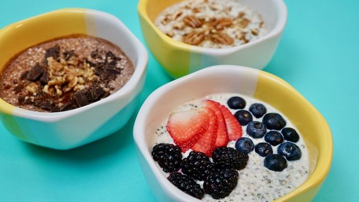 Three colorful bowls of faux overnight "oats" on a colorful blue countertop