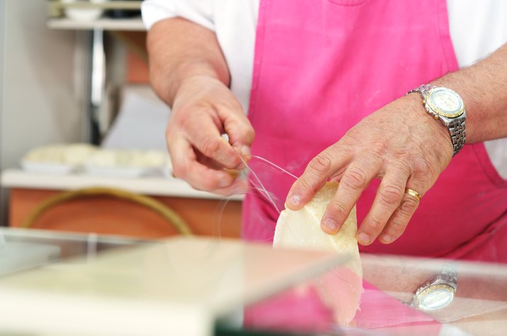 cheesemonger cutting parmesan with wire