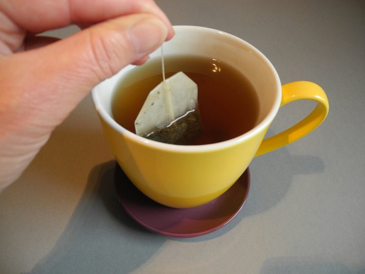 Cropped Hand Dipping Teabag In Cup At Home