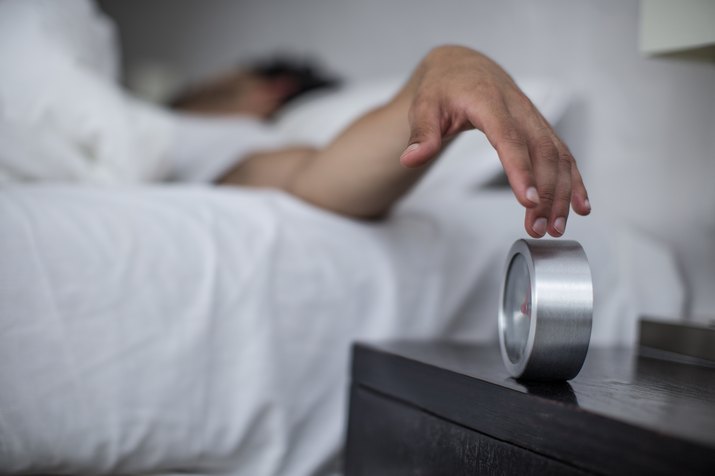 Man reaching to turn off alarm clock