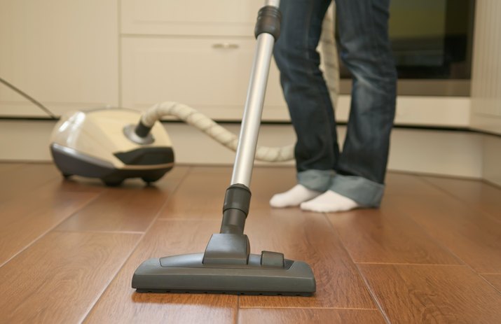 Germany, Brandenburg, Young woman cleaning floor with vacuum cleaner