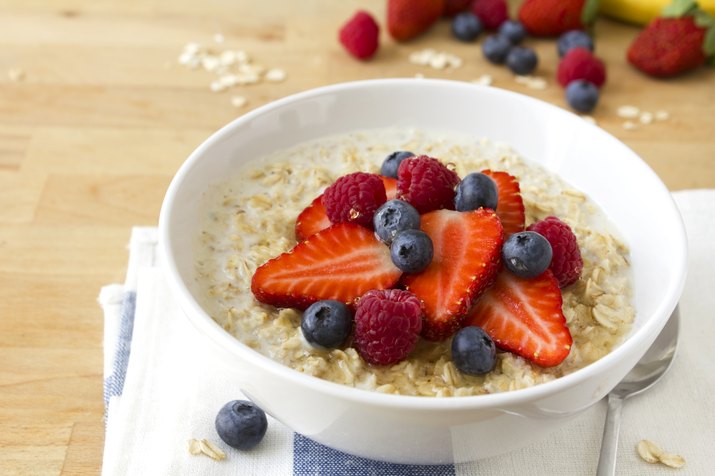 A bowl of oatmeal with blue berries and strawberries