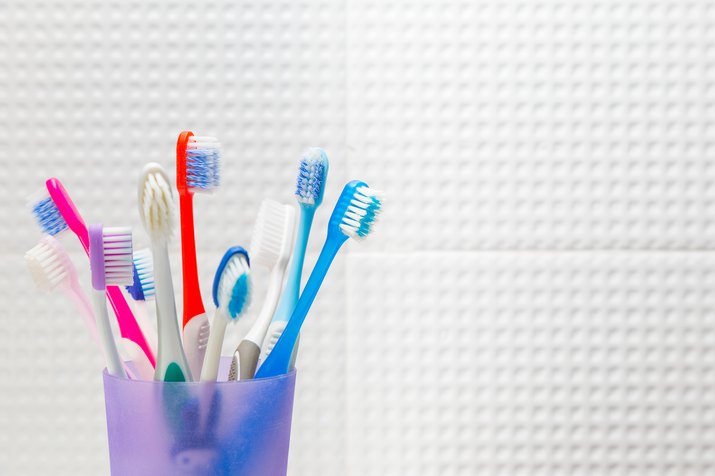 Close-Up Of Colorful Toothbrushes In Container Against White Wall