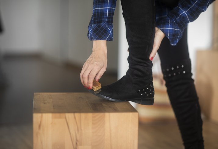 Woman standing in the living room cleaning her boots