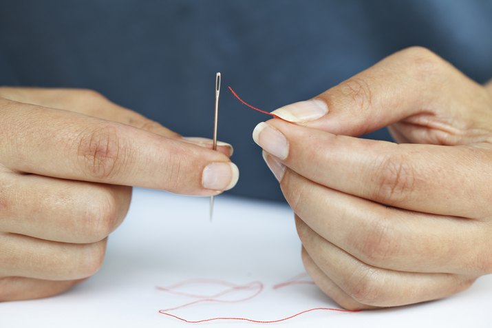 Woman threading needle, close-up