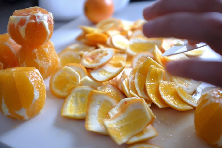Cropped Hand Reaching For Oranges On Table