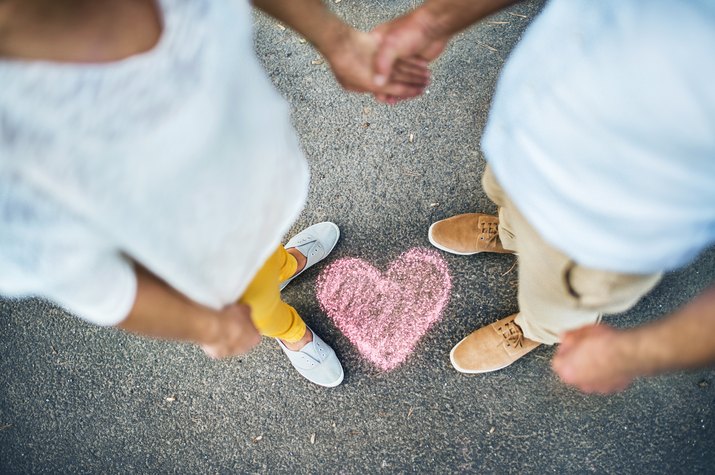 A midsection view of senior couple standing on a road, with chalk heart by their feet.