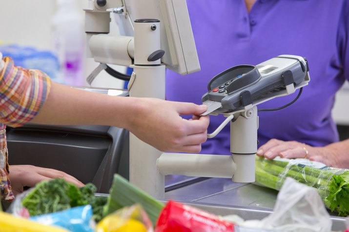 Close Up Of Woman Paying For Shopping At Supermarket Checkout