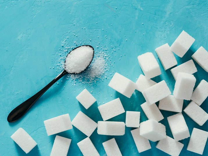 Top view of white sugar cubes on blue concrete background