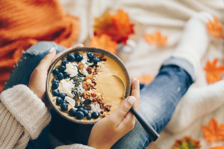 Woman holding a pumpkin smoothie bowl - Autumn concept