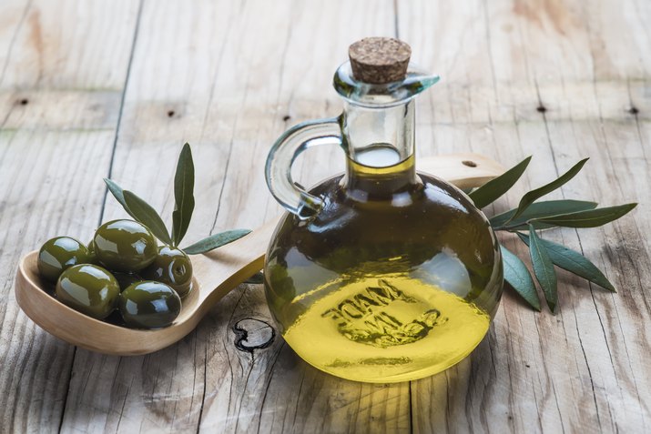 Olive oil bottle and a spoon with olives
