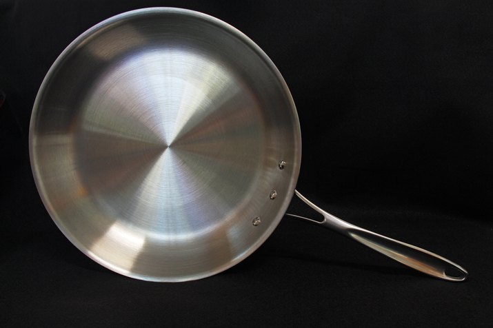 A ten-inch stainless steel frying pan on black background