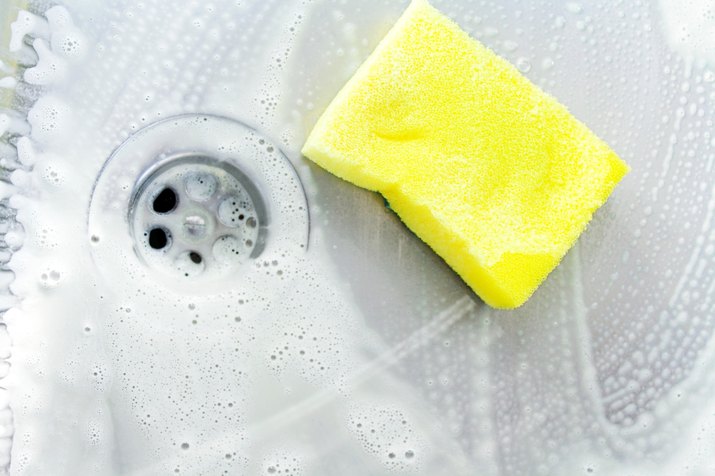 cleaning a sink with yellow sponge