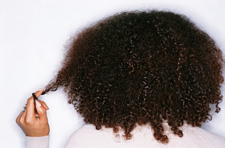 Young woman twisting hair round finger, rear view