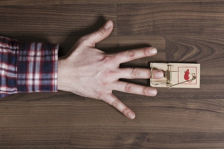 A man's finger trapped in a mousetrap, close-up of hand