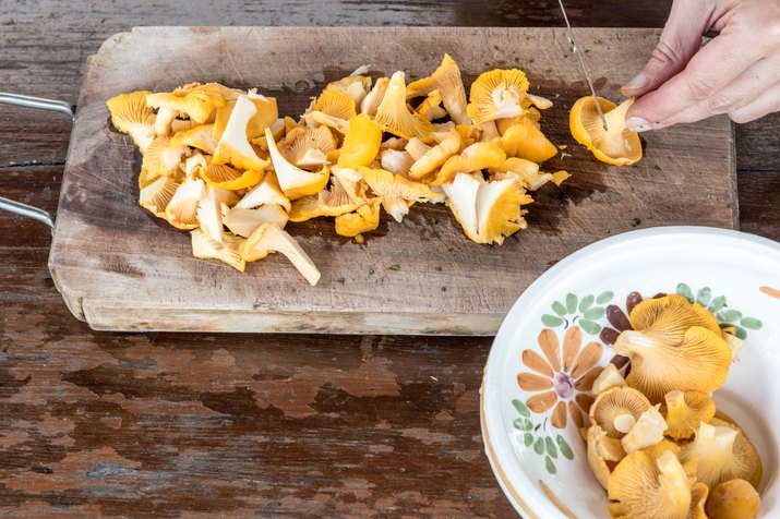Slicing Chanterelle Mushrooms On Wooden Chopping Board