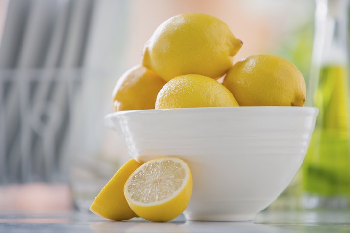 White bowl filled with lemons on counter.