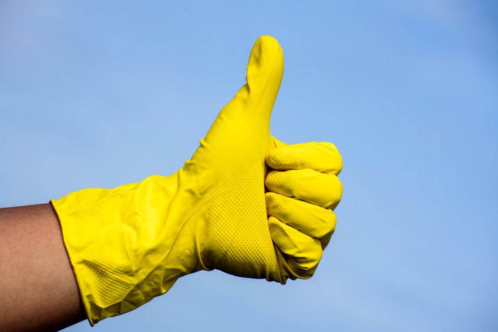 Hand in yellow protective glove showing thumbs up sign
