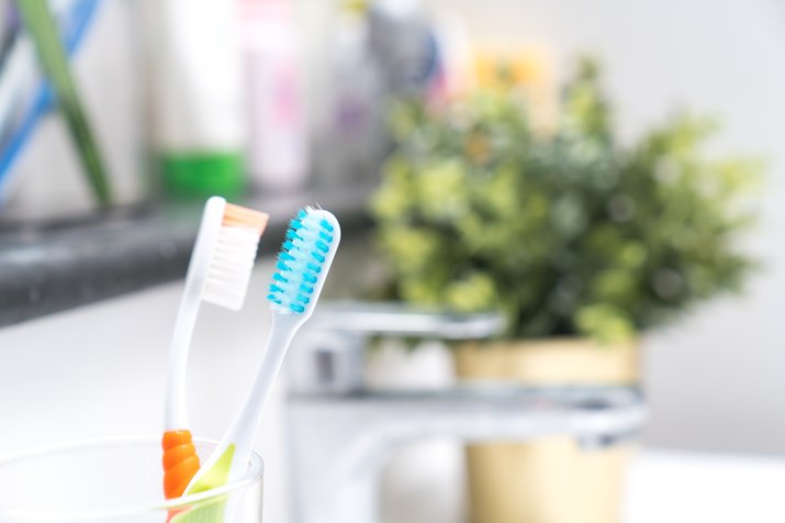 Toothbrush in the glass for toothbrush on the wash basin on the wall background in the bathroom.