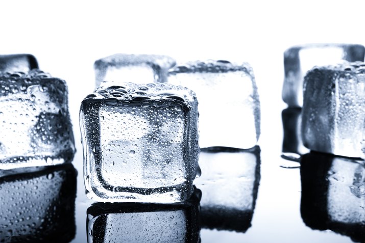 Close-Up Of Ice Cubes On Table Against White Background