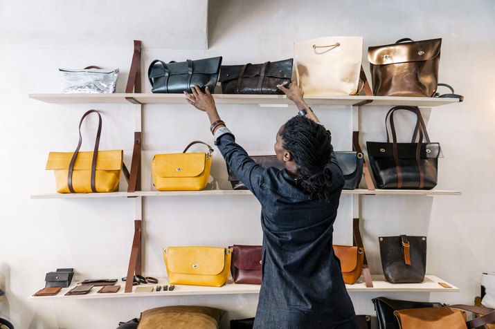 An entrepreneur handbag designer arranges her goods inside her store.