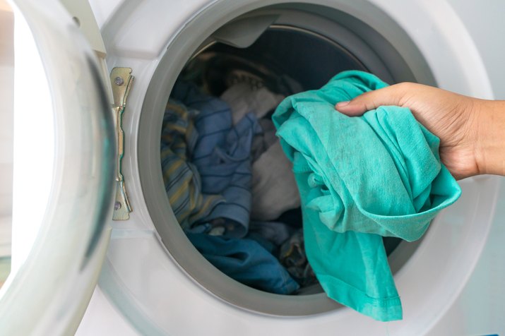 Cropped Hand Of Person Putting Laundry In Washing Machine