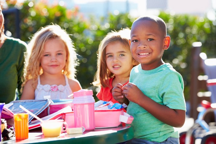 Elementary Pupils Sitting At Table Eating Lunch