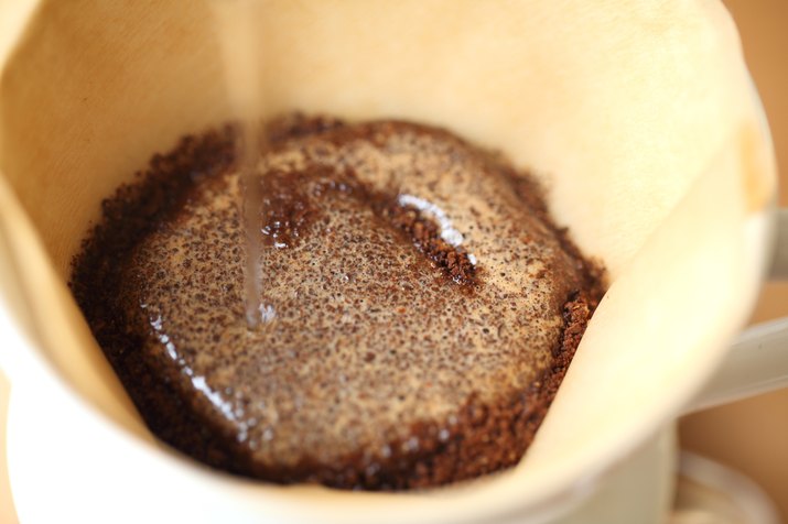 Water pouring onto ground coffee in filter, Oakland, California, USA