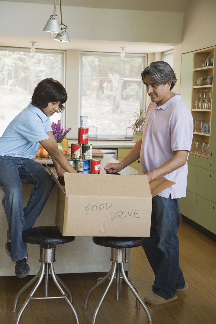 Father and son packing box of canned food