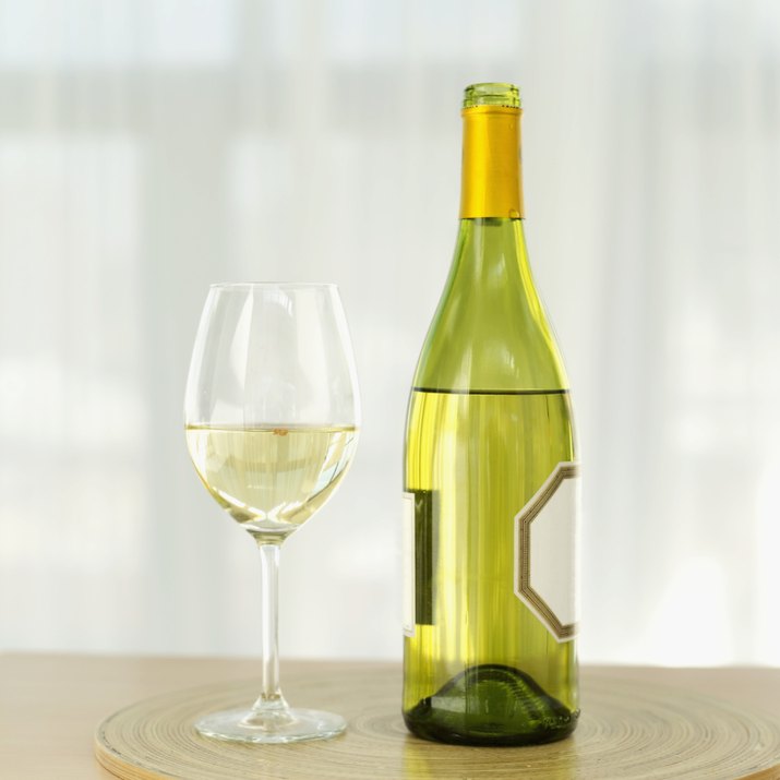 close-up of a bottle of white wine with a wineglass on a table