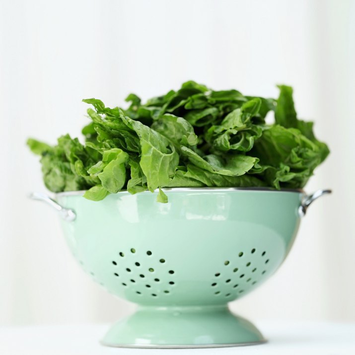 a metal colander with green leaves