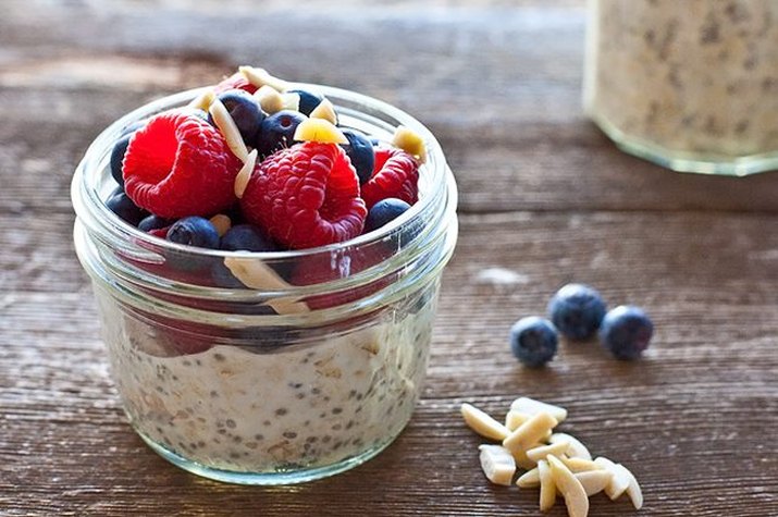 A small mason jar filled with overnight oatmeal chia pudding with cardamom and berries.