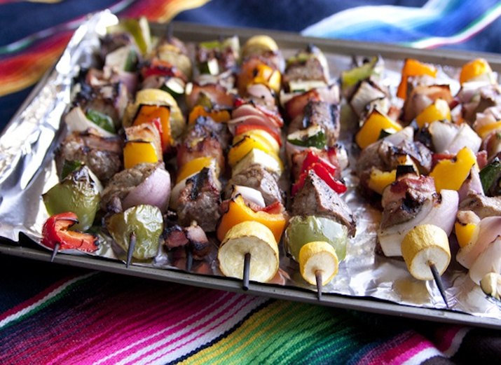 Grilled steak and bacon shish kebabs with peppers and onion on baking sheet.