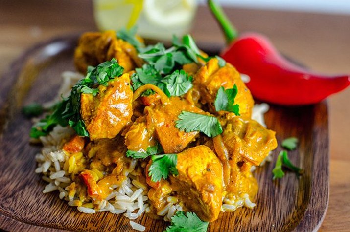 A plate of bright orange curry on a bed of rice.
