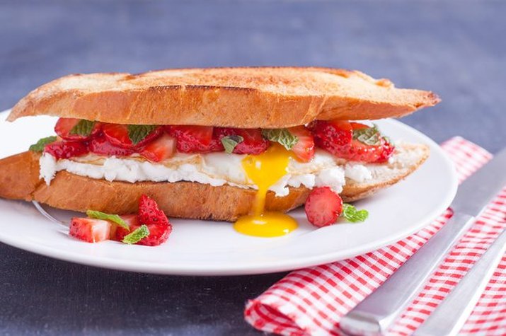 A fried egg sandwich made with strawberries and mint.