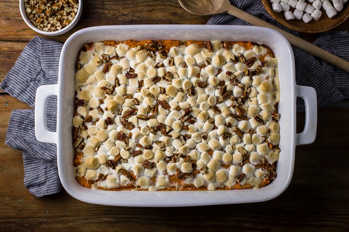 A large sweet potato casserole topped with pecans and marshmallows