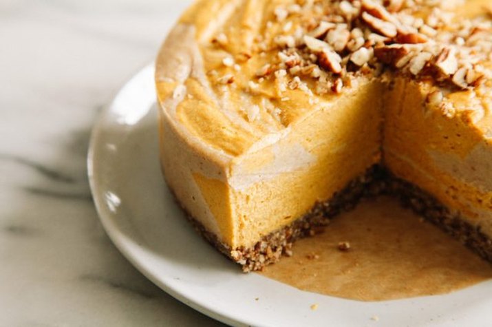 A bright orange raw pumpkin swirl cheesecake topped with pecans.